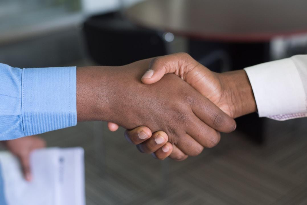 Two sales leaders shake hands after implementing technological improvements in their strategies. 